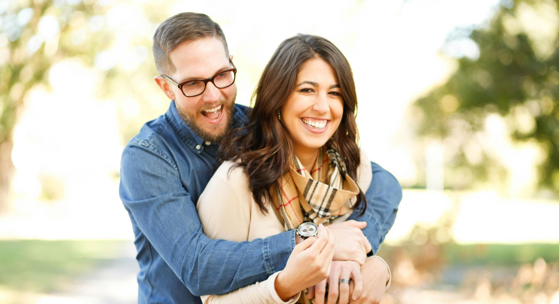 A happy couple enjoying an outdoor engagement photoshoot with laughter and love.